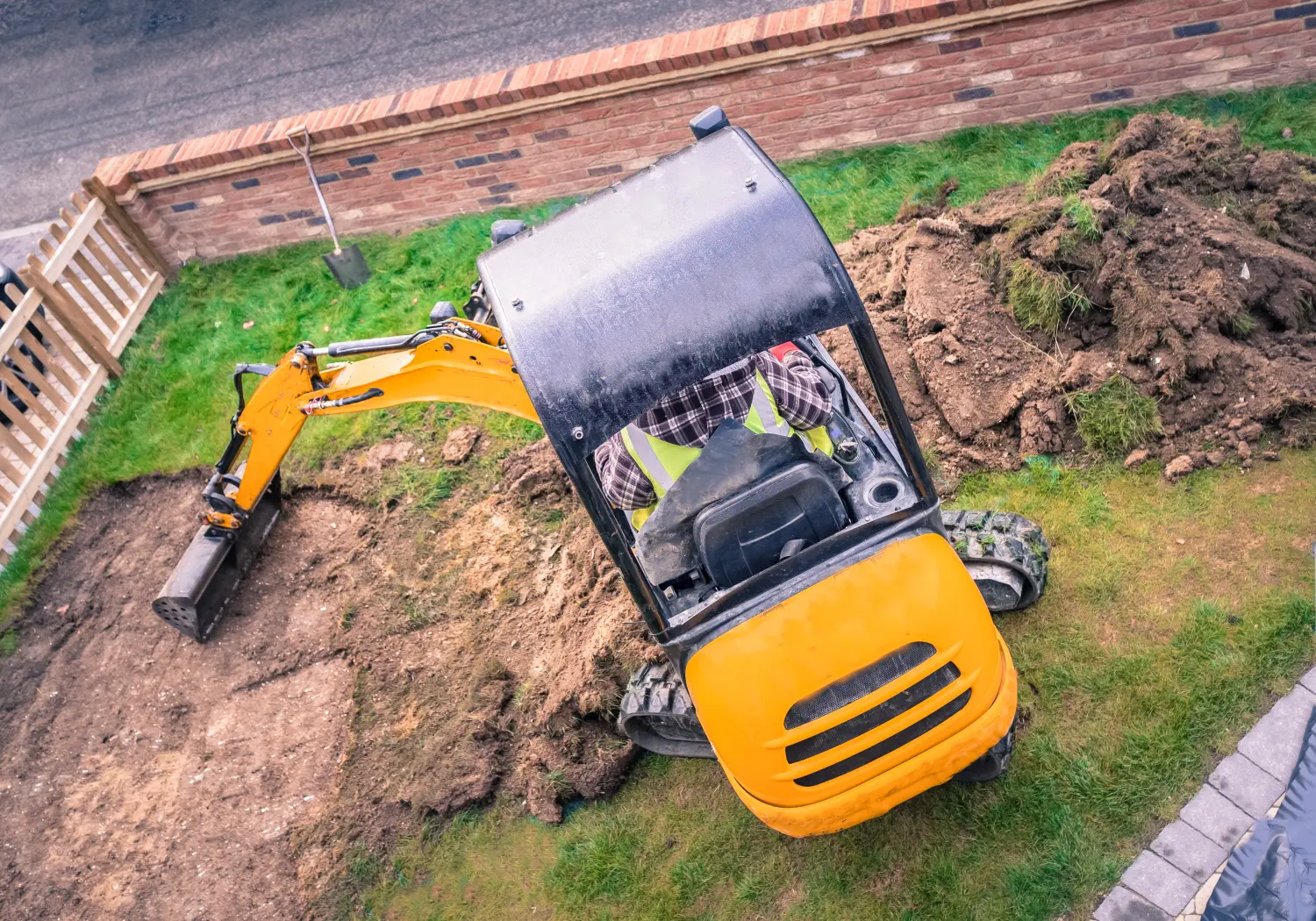 CMD GrünBau - Garten- und Landschaftsbau - Von oben gesehen entfernt ein Bagger Rasen im Vorgarten, Garten zur Landschaftsgestaltung mit Kunstrasen.